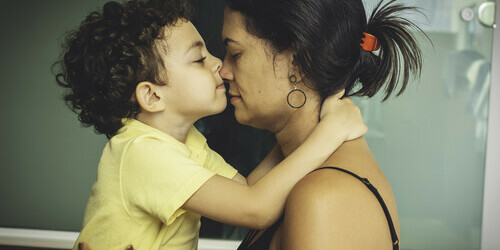 A little boy kisses his mother's nose.