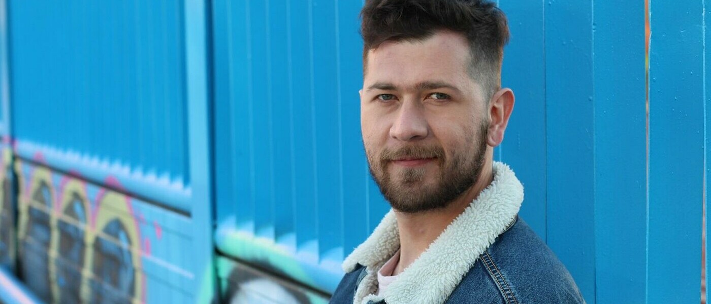 Man in jacket in front of blue background